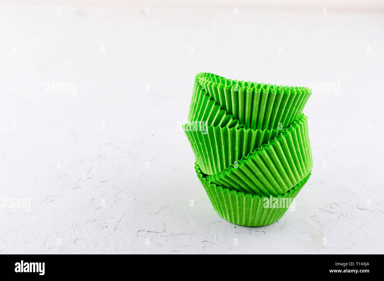 Brightly green colored paper baking cups for cupcakes or muffins on light grey conkrete background, copy space Stock Photo