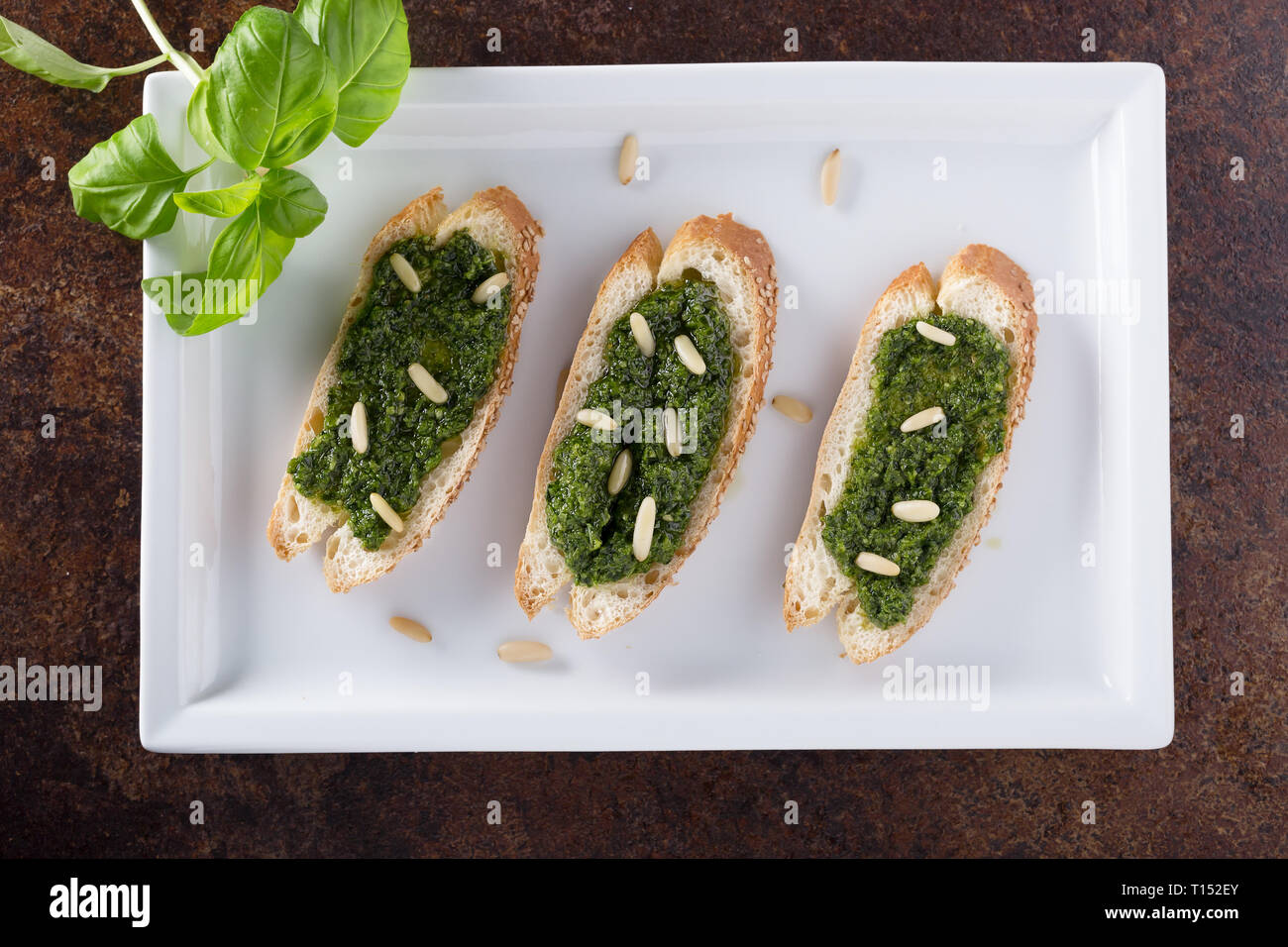 Bruschetta with basil pesto sauace and pinoli, on a white plate. Healthy food, diet and cooking concept. Specialties of Italian cuisine. Selective sof Stock Photo