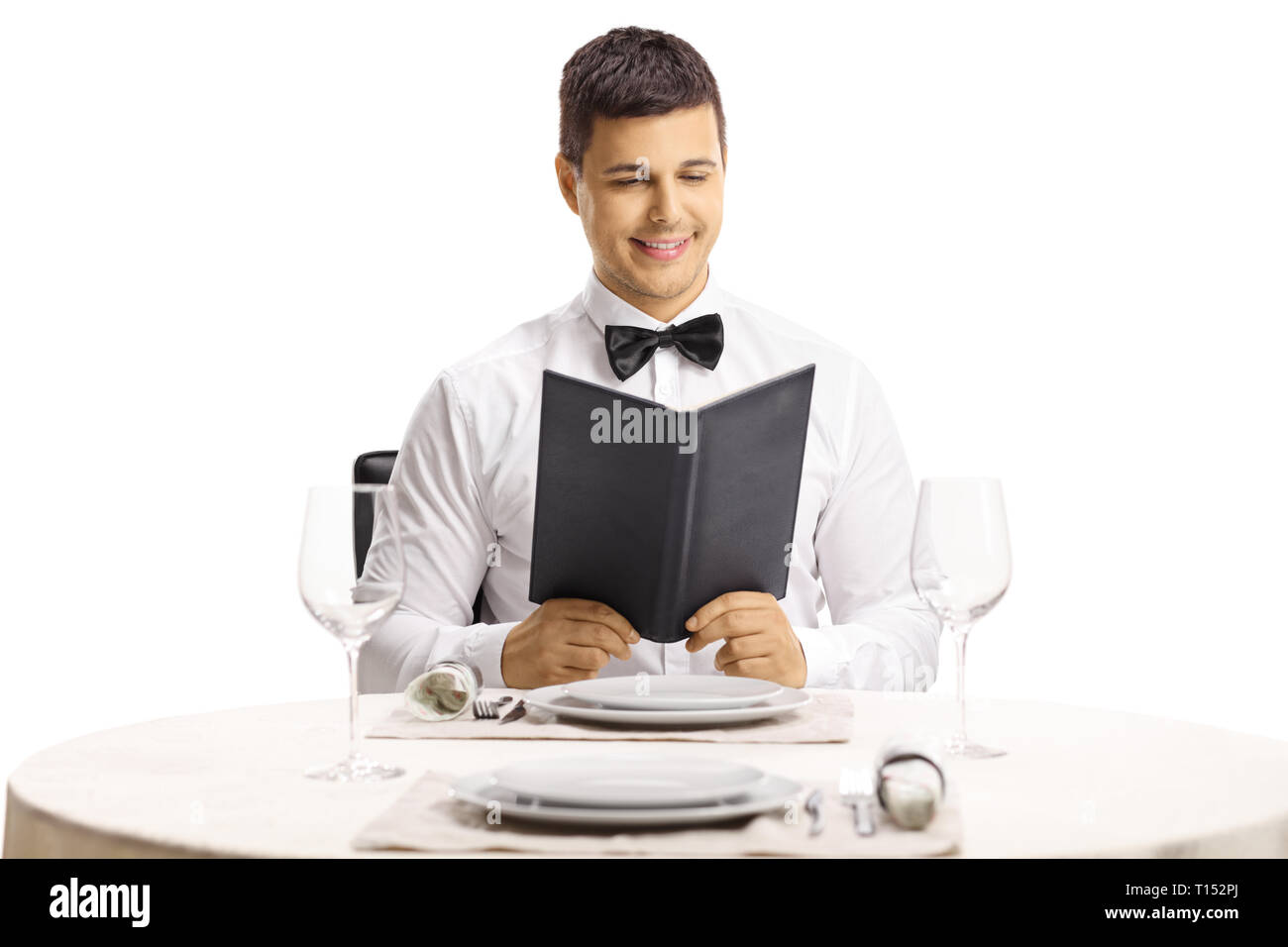 Young handsome man at a restaurant table reading a menu isolated on white background Stock Photo