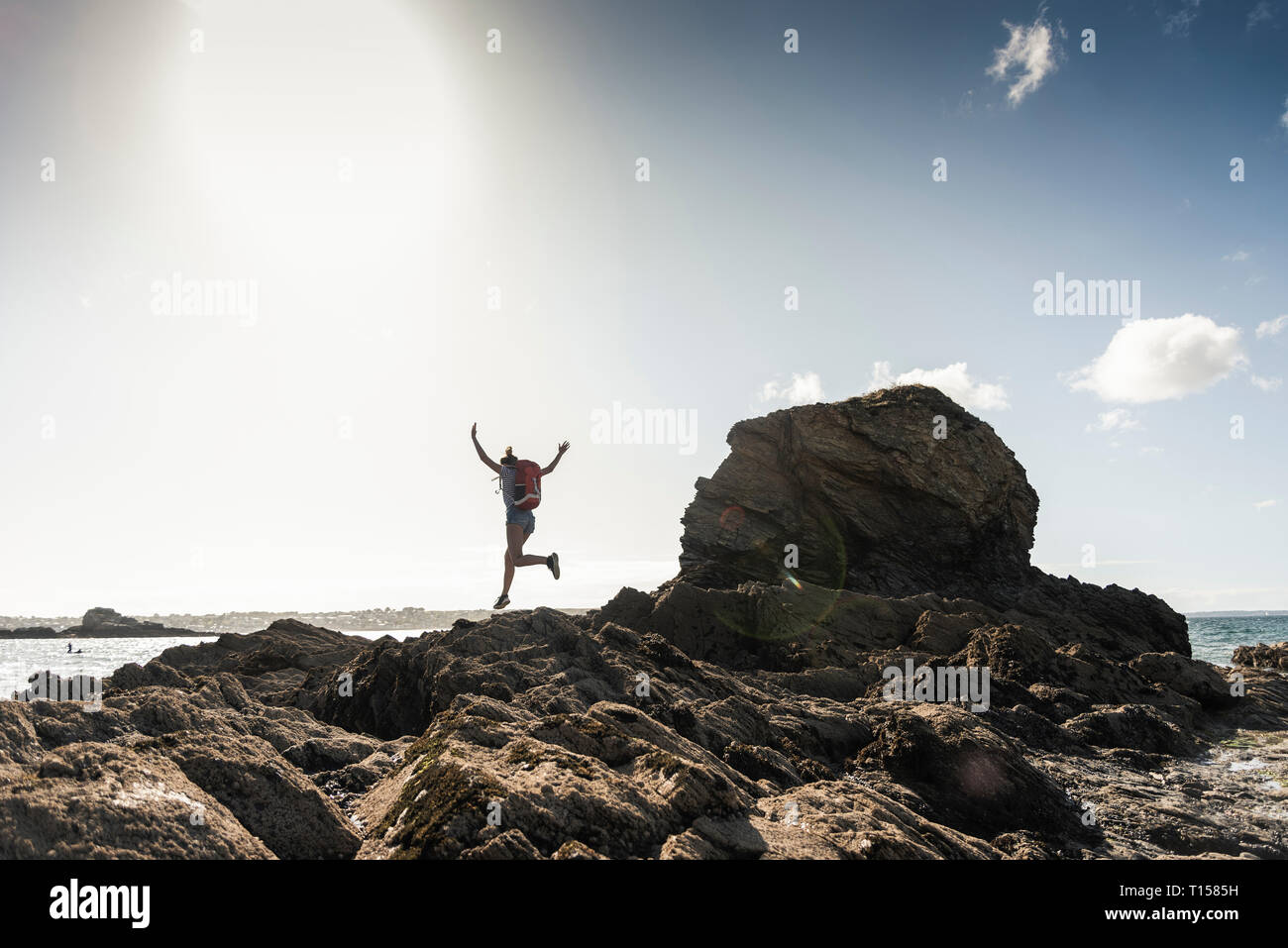 Young woman runnning and jumping on a rocky beach Stock Photo