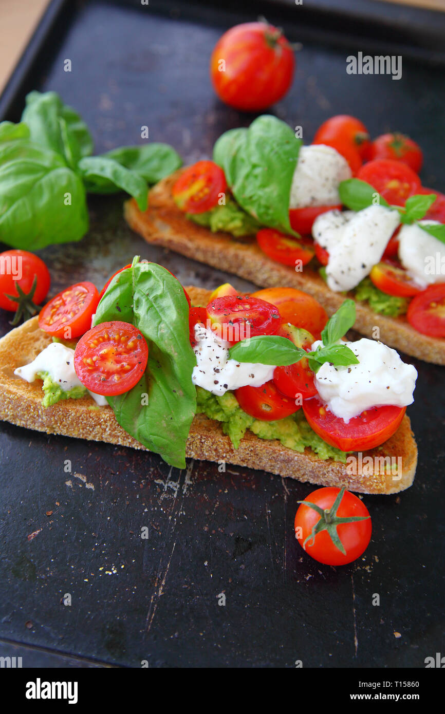 Closeup of toast spread with avocado, topped with burrata cheese