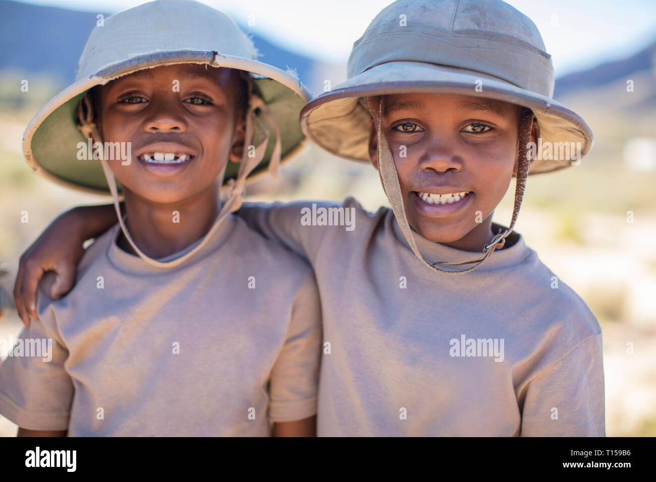 Portrait of two smiling boys embracing wearing pith helmet Stock Photo