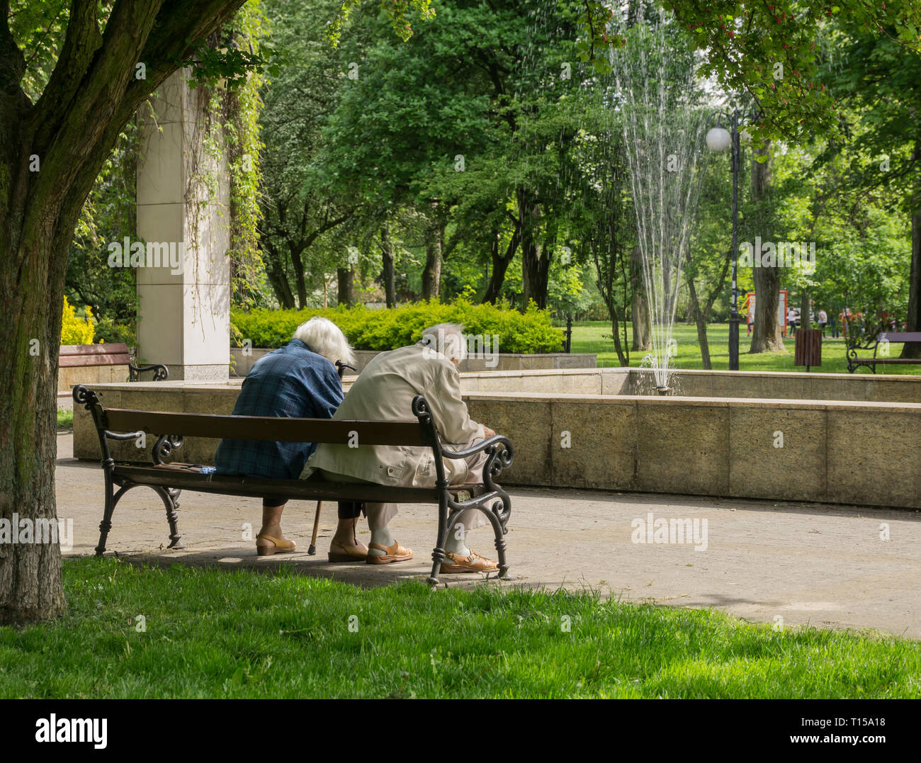 Old couple seating on bench in spring park Stock Photo