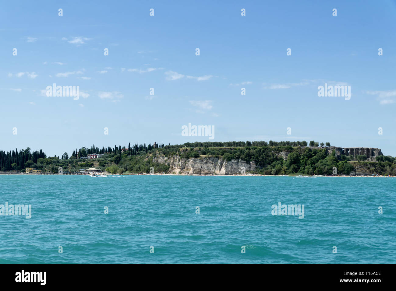 Stony Beach of Sirmione town on Garda Lake with view of Grottoes of Catullus (Grotte di Catullo), the ruins of a Roman villa built at the end of the 1 Stock Photo