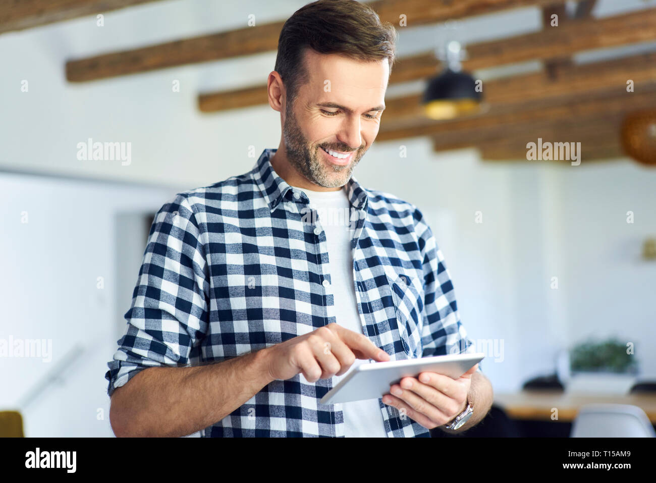 Man using tablet at home and smiling Stock Photo