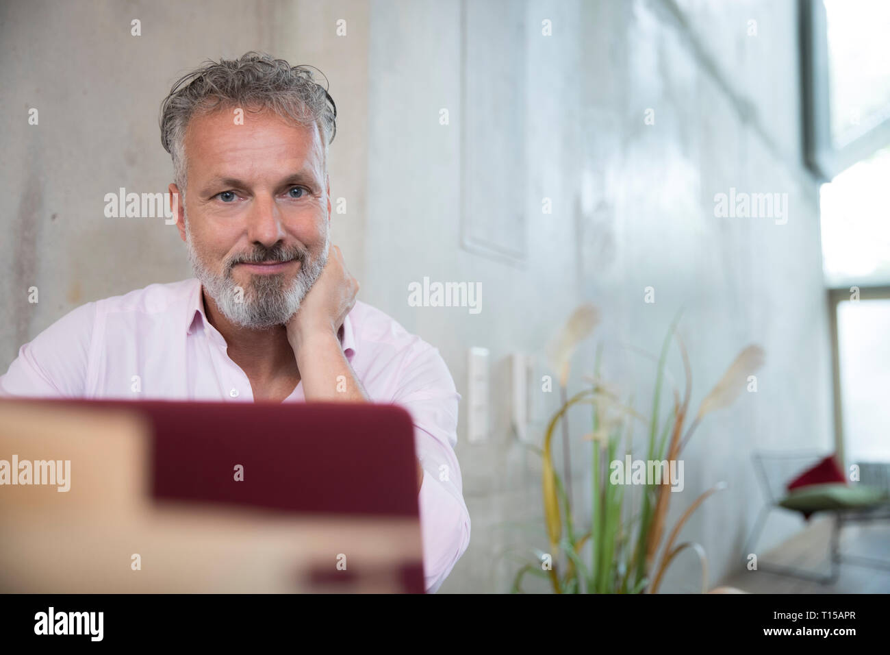 Portrait of confident businessman in a loft using laptop Stock Photo