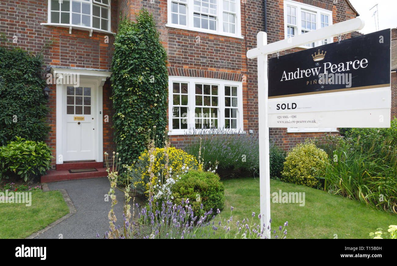 London, UK - July 15, 2014. A London estate agent sold sign is displayed outside a suburban semi-detached house in Pinner, northwest London. Stock Photo