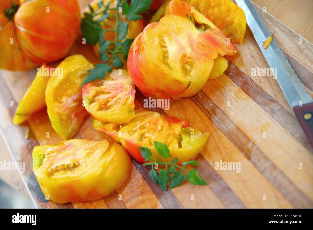 Fresh and colorful tomatoes on a cutting board with a serrated knife Stock Photo Alamy