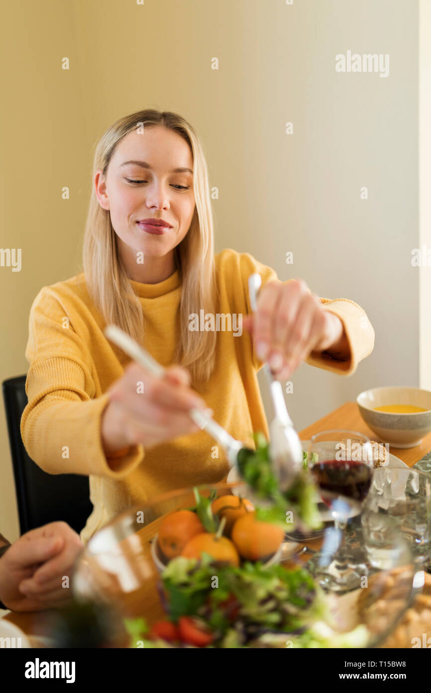 Young woman eating salad at a lunch with friends Stock Photo