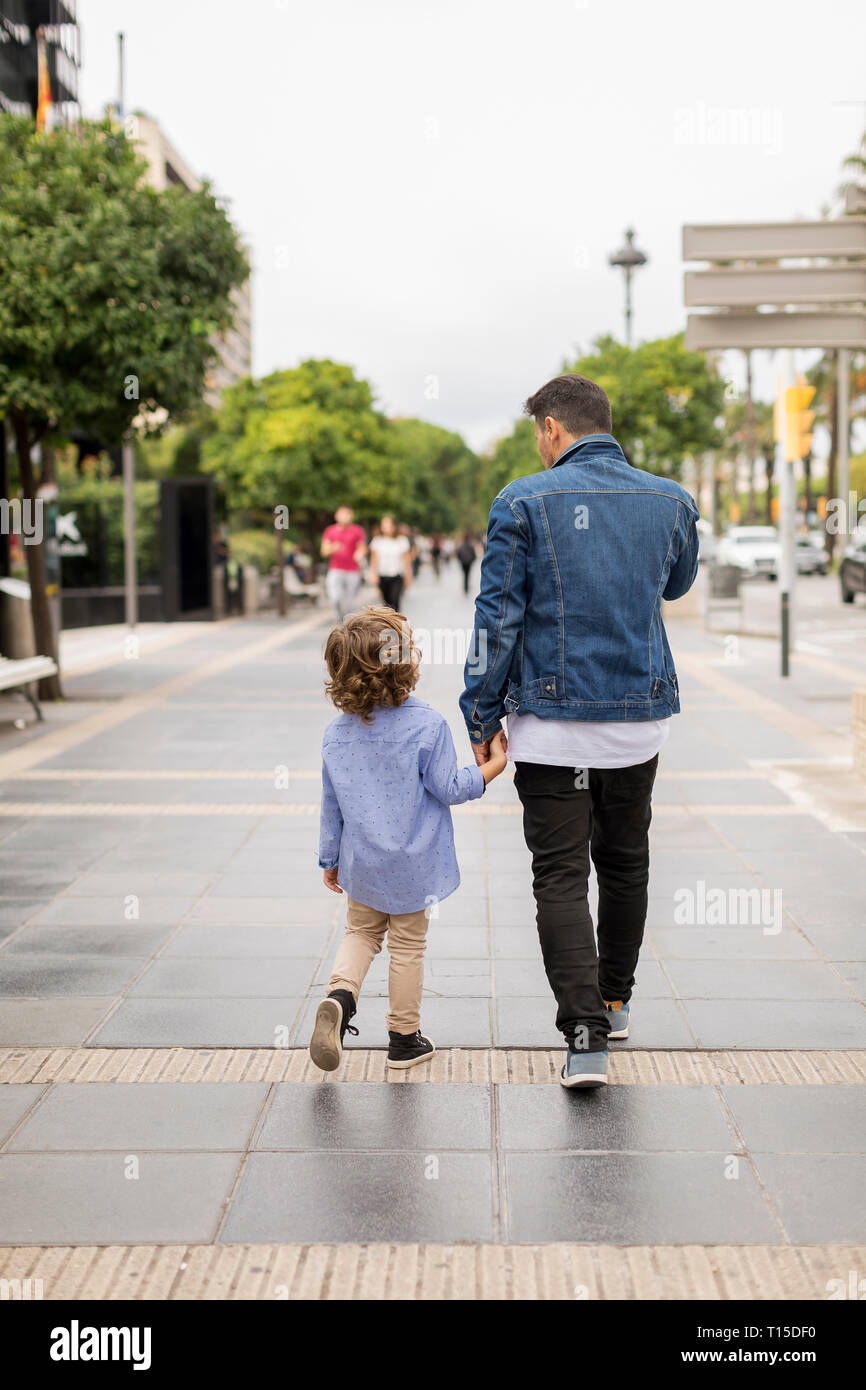 Rear view of father and son walking hand in hand in the city Stock ...