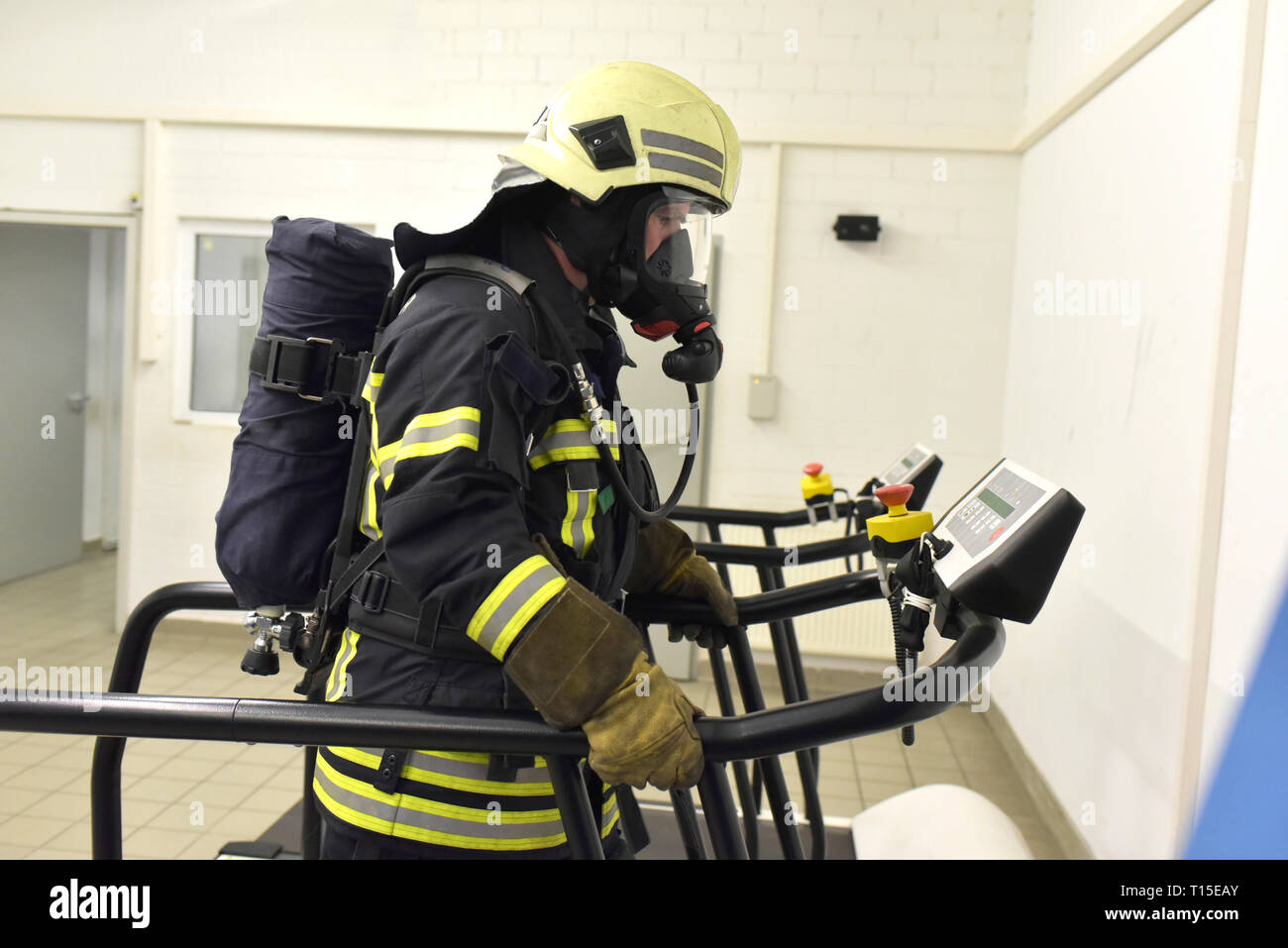 Firefighter with respirator and air tank exercising on treadmill Stock Photo