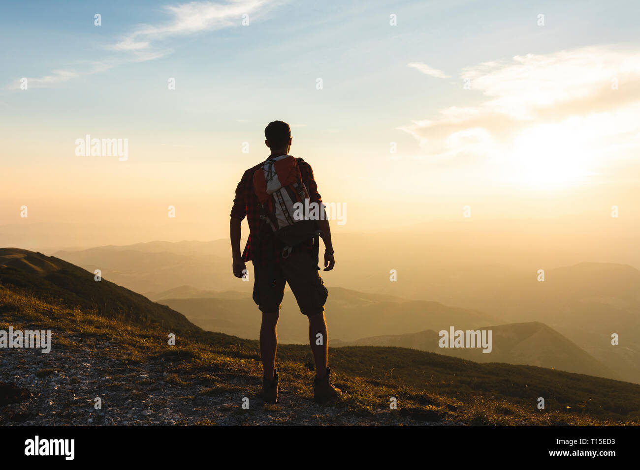 Italy, Monte Nerone, hiker on top of a mountain looking at panorama at sunset Stock Photo