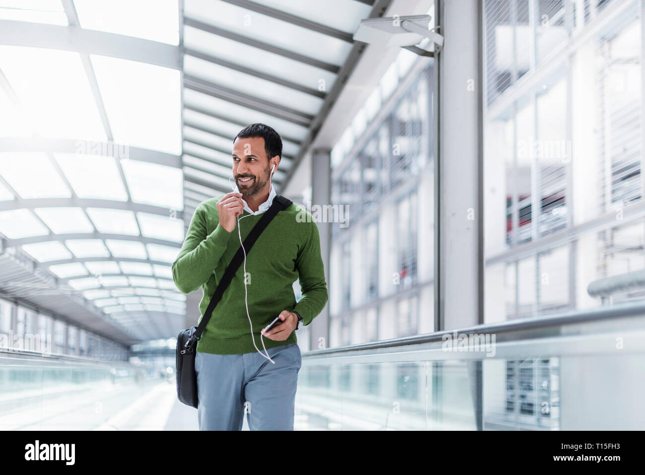 Businessman using smartphone on moving walkway Stock Photo