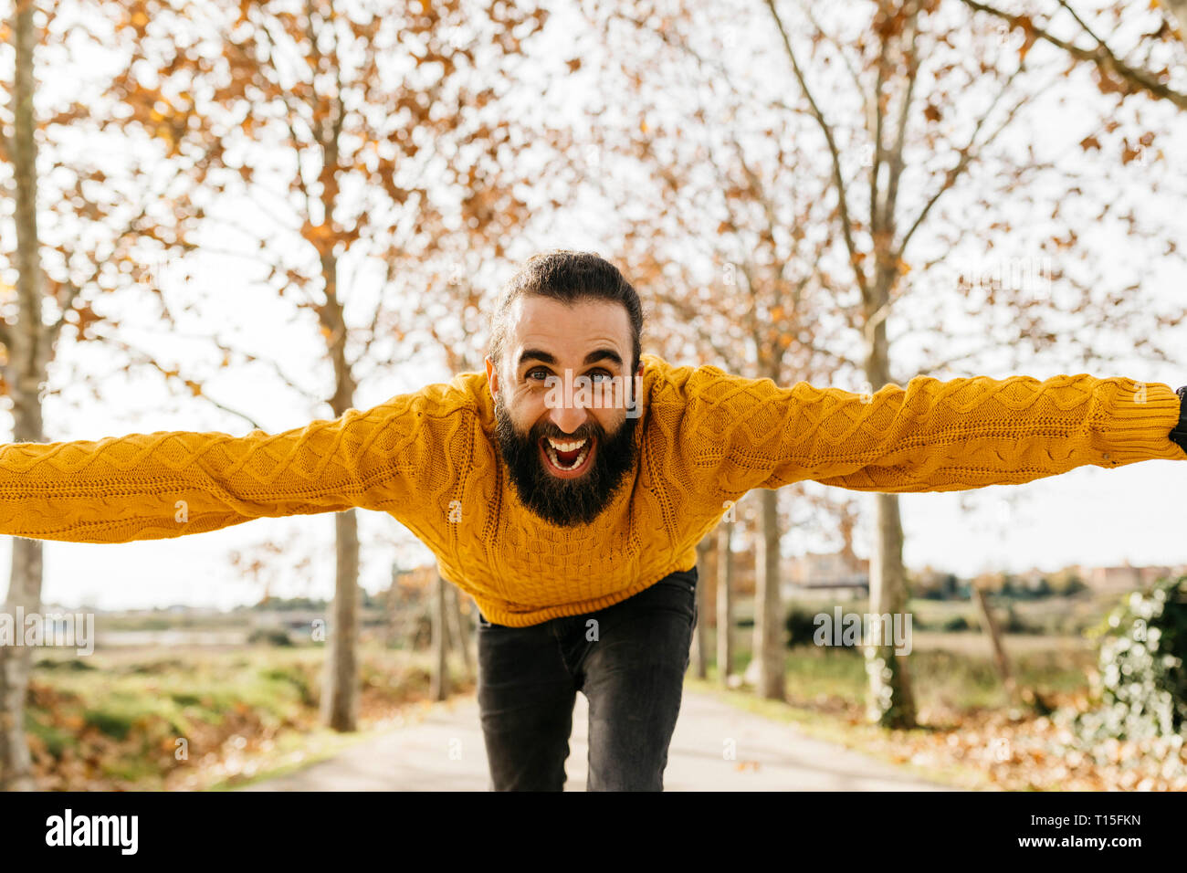 Young man with open arms and happy in a park in autumn Stock Photo