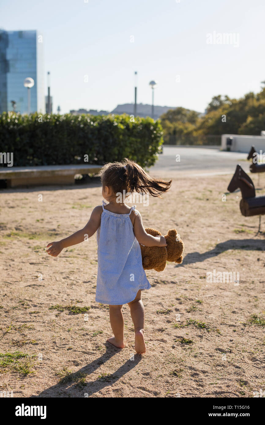 Rear view of little girl with teddy on a playground Stock Photo - Alamy