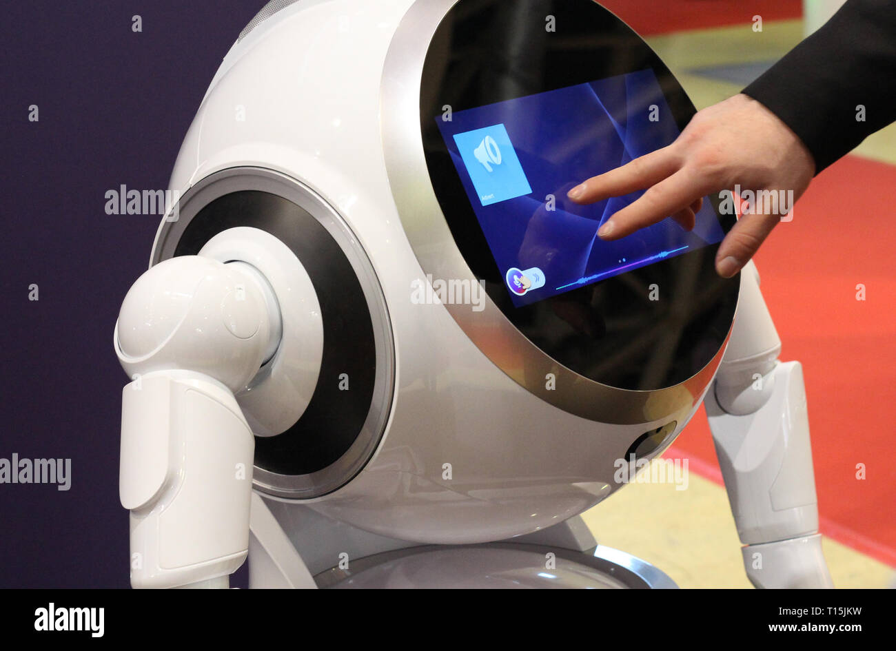 Smart robot for help around the house. Male hand adjusts the settings of the robot. Hand on the background of the display to set up a robot assistant. Stock Photo