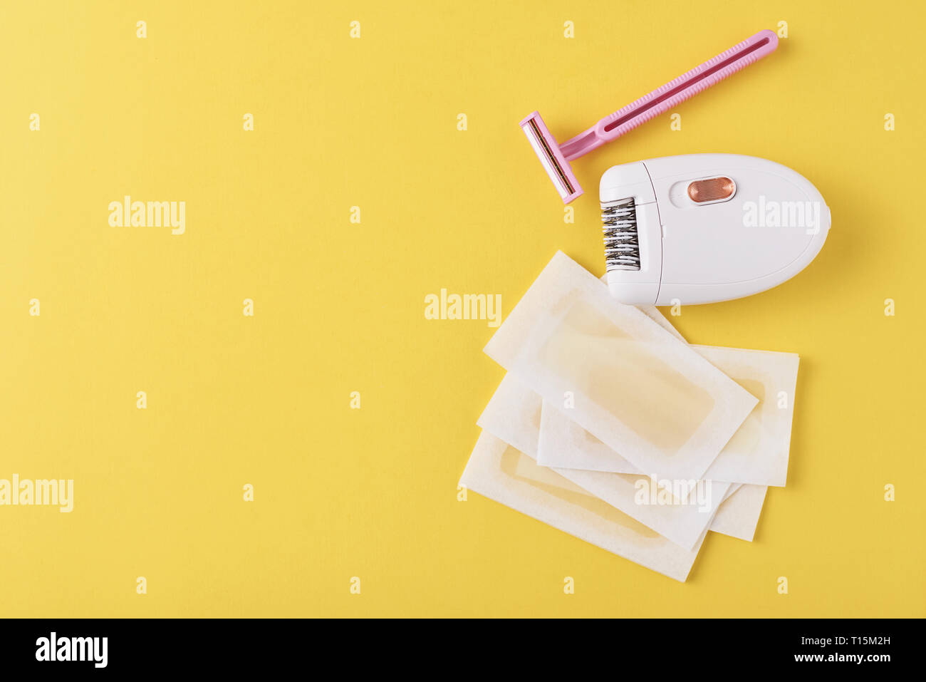 Epilator, razor for shaving and wax strips on yellow background with ...
