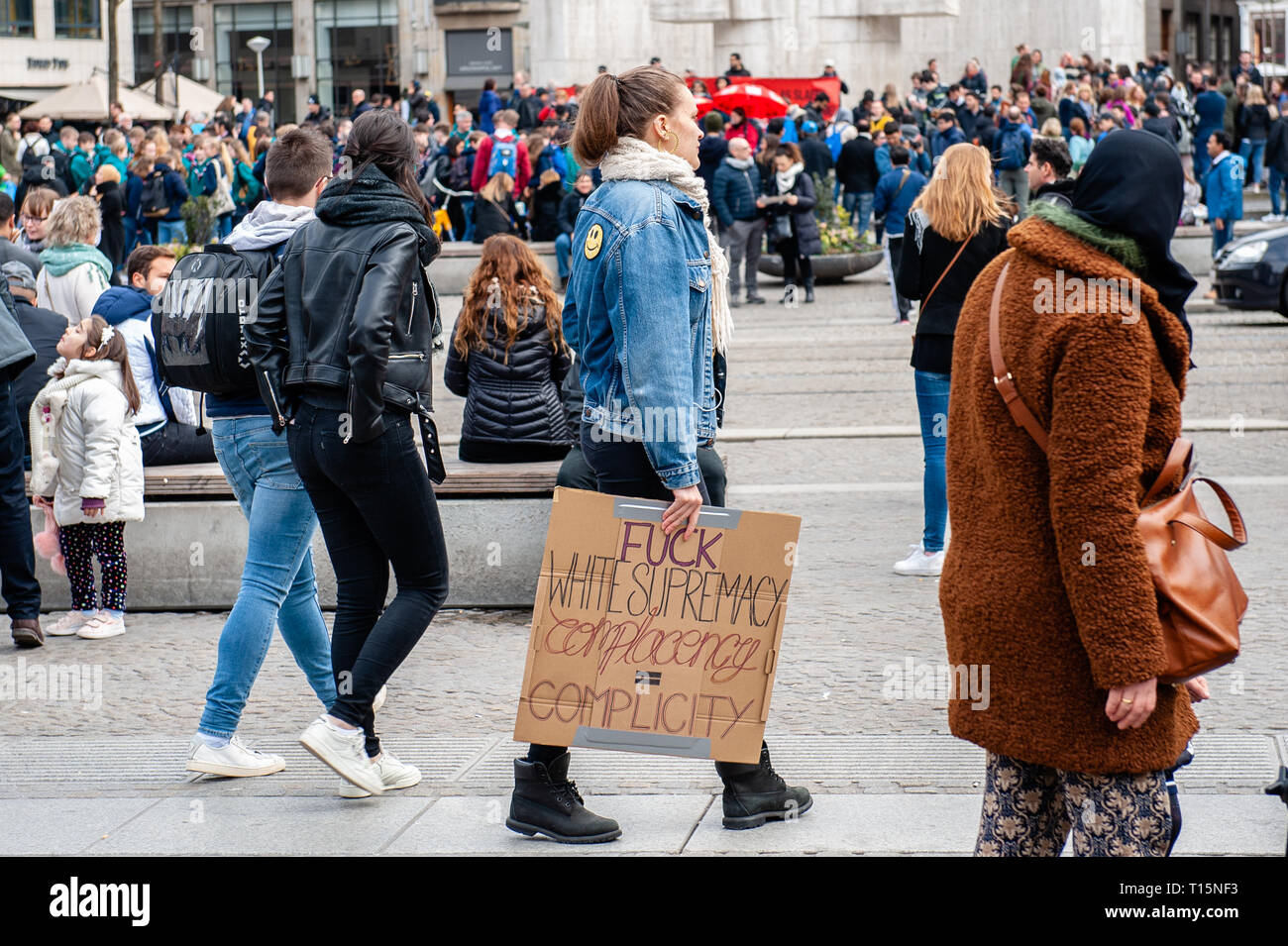 Amsterdam, North Holland, Netherlands. 23rd Mar, 2019. A woman is seen walking around the Dam square while holding a placard during the demonstration.Thousands of people gathered at the Dam square in the center of Amsterdam to demonstrate against racism and discrimination. They ask for diversity and solidarity, against all forms of racism and discrimination. Also, against the two political far-right parties in The Netherlands, the PVV and the FvD which have increased their power during the last elections in the country. A small far-right group showed up during the walk holding two big placa Stock Photo