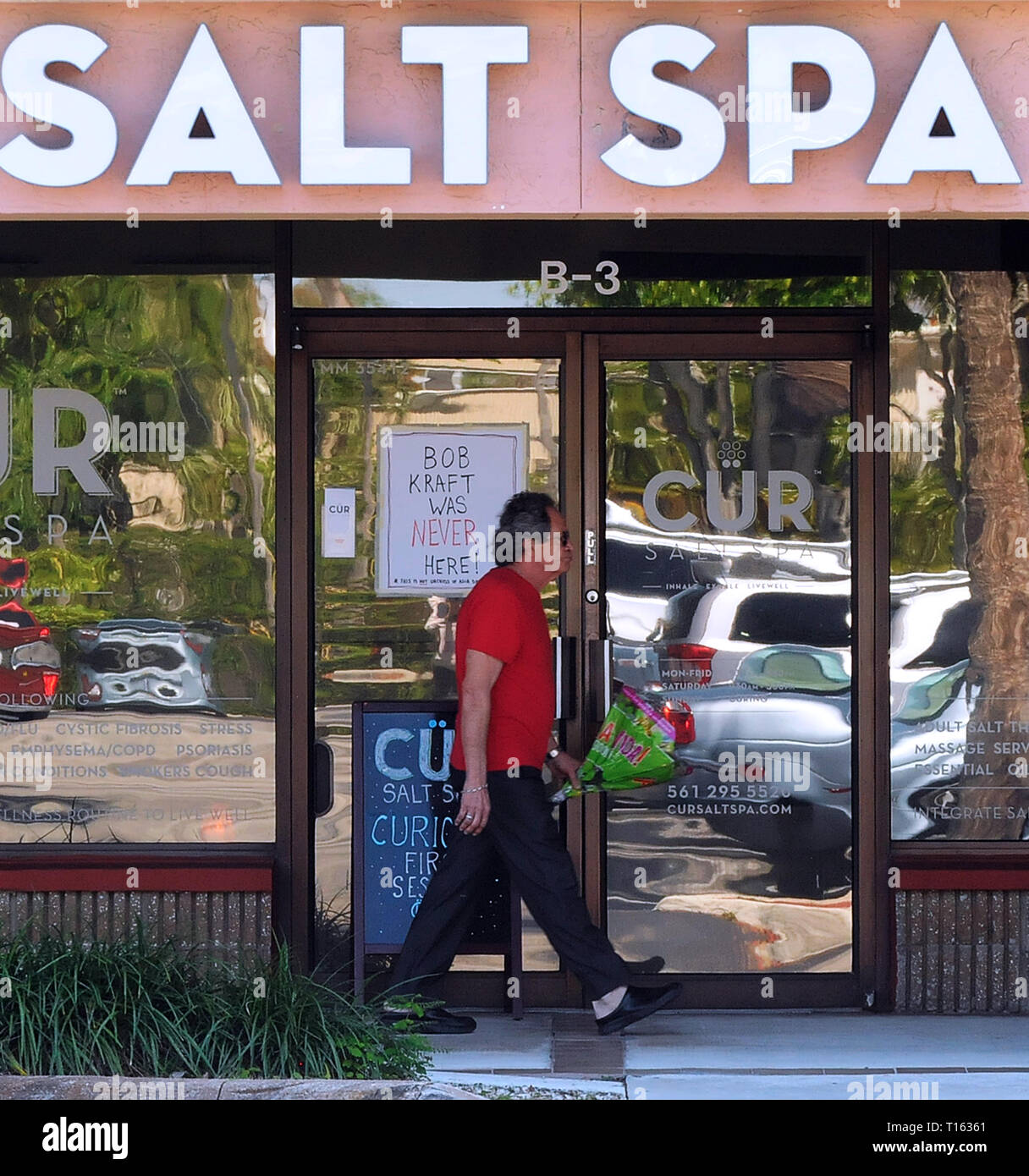 Florida, USA. 22nd Mar, 2019. A man walks past a sign on the front door of the Cur Salt Spa in Jupiter, Florida which reads, 'Bob Kraft Was Never Here!' The business is in the same shopping plaza as the Orchids of Asia Day Spa where New England Patriots owner Robert Kraft and others were allegedly caught soliciting prostitution in February 2019. Credit: Paul Hennessy/Alamy Stock Photo