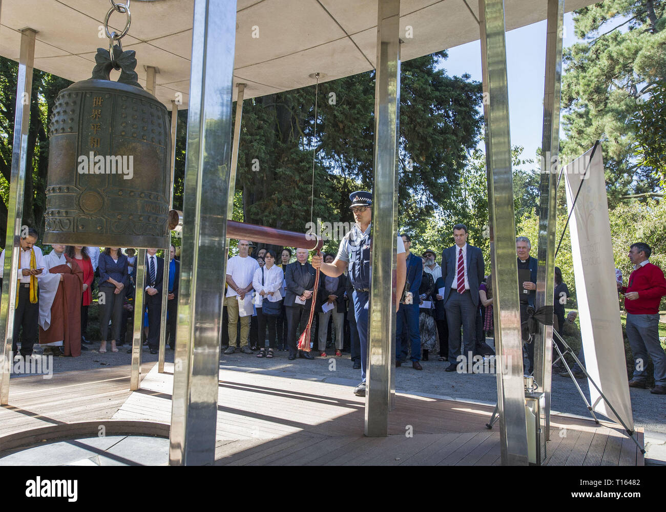 Christchurch, Canterbury, New Zealand. 24th Mar, 2019. A police officer sounds the Peace Bell in the Botanic Gardens during an interfaith service. Some 24 different faiths were represented at the service, with the Peace Bell sounding 50 times in memory of those killed at the Al Noor and Linwood mosques on 15 March. Credit: PJ Heller/ZUMA Wire/Alamy Live News Stock Photo