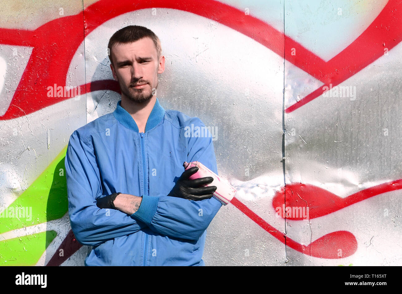 The graffiti artist with spray can poses against the background of a ...
