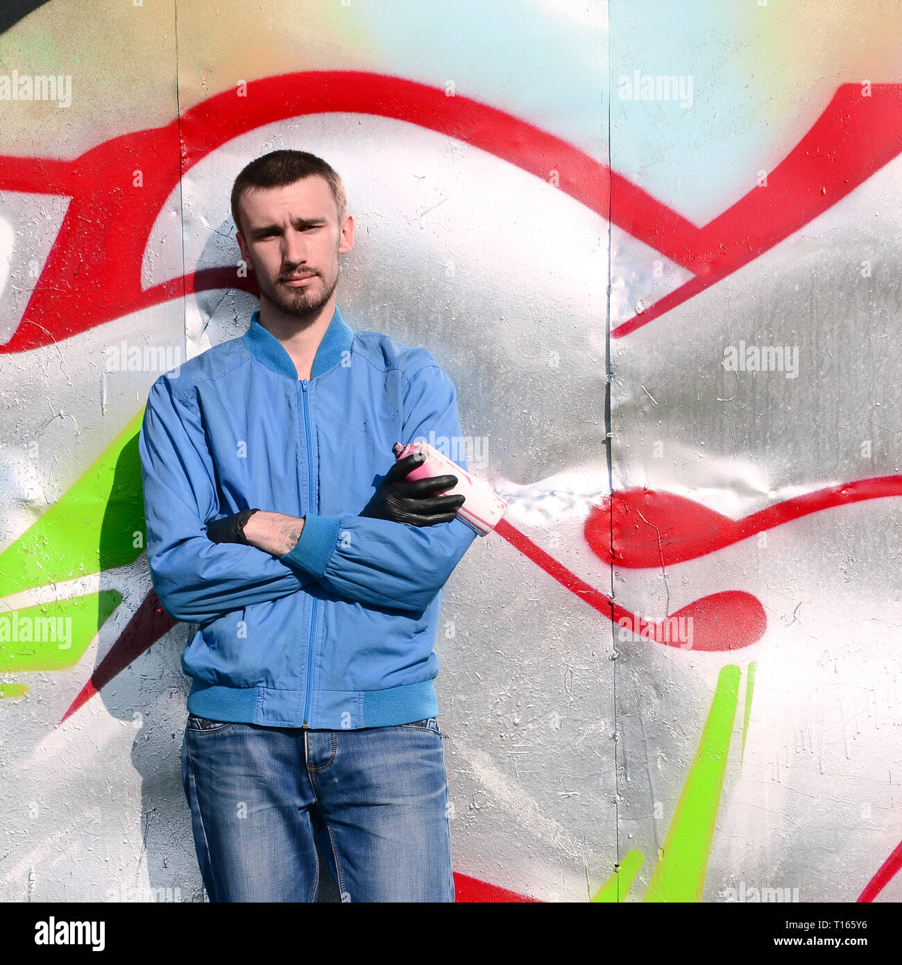 The graffiti artist with spray can poses against the background of a ...