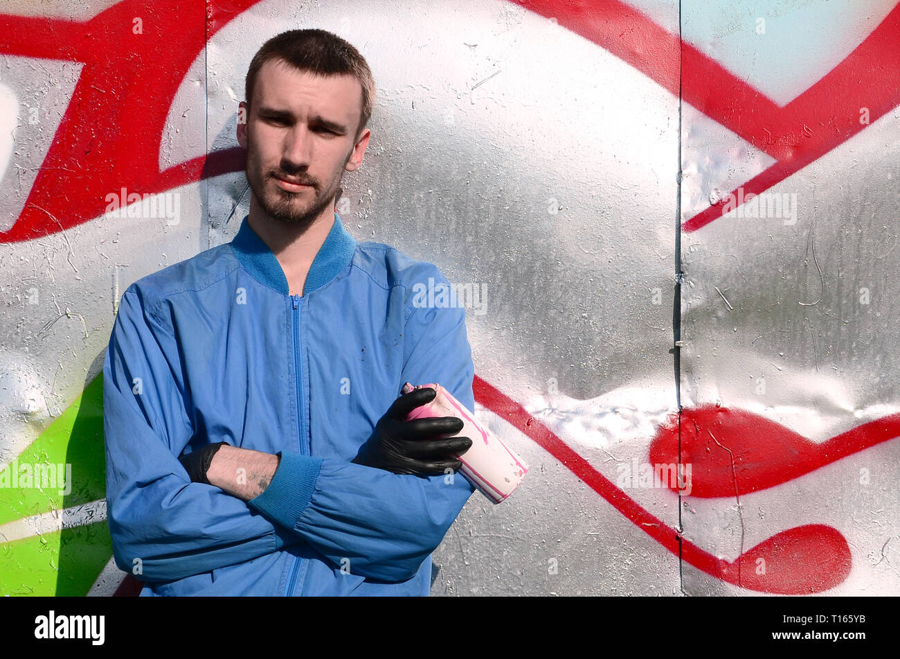 The graffiti artist with spray can poses against the background of a ...