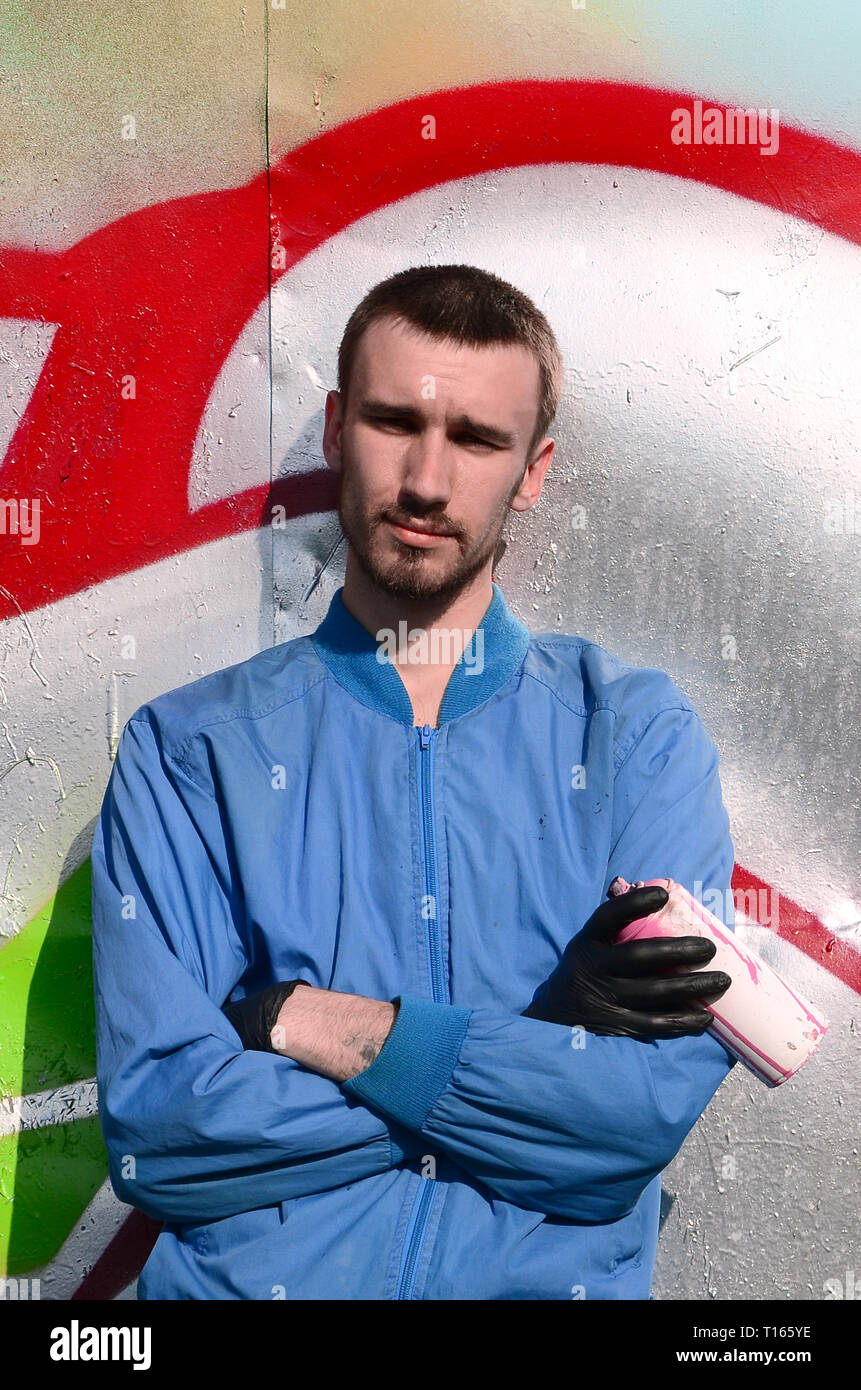 The graffiti artist with spray can poses against the background of a ...