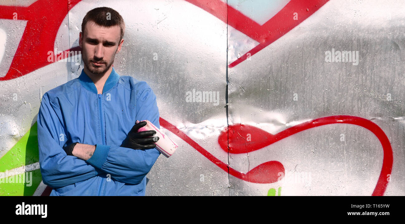 The graffiti artist with spray can poses against the background of a ...