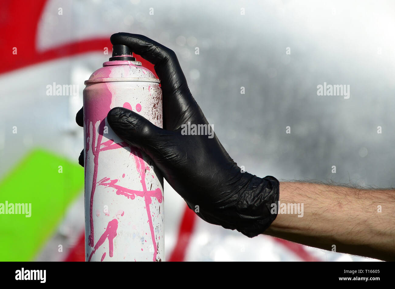 A hand with a spray can that draws a new graffiti on the wall. Photo of ...