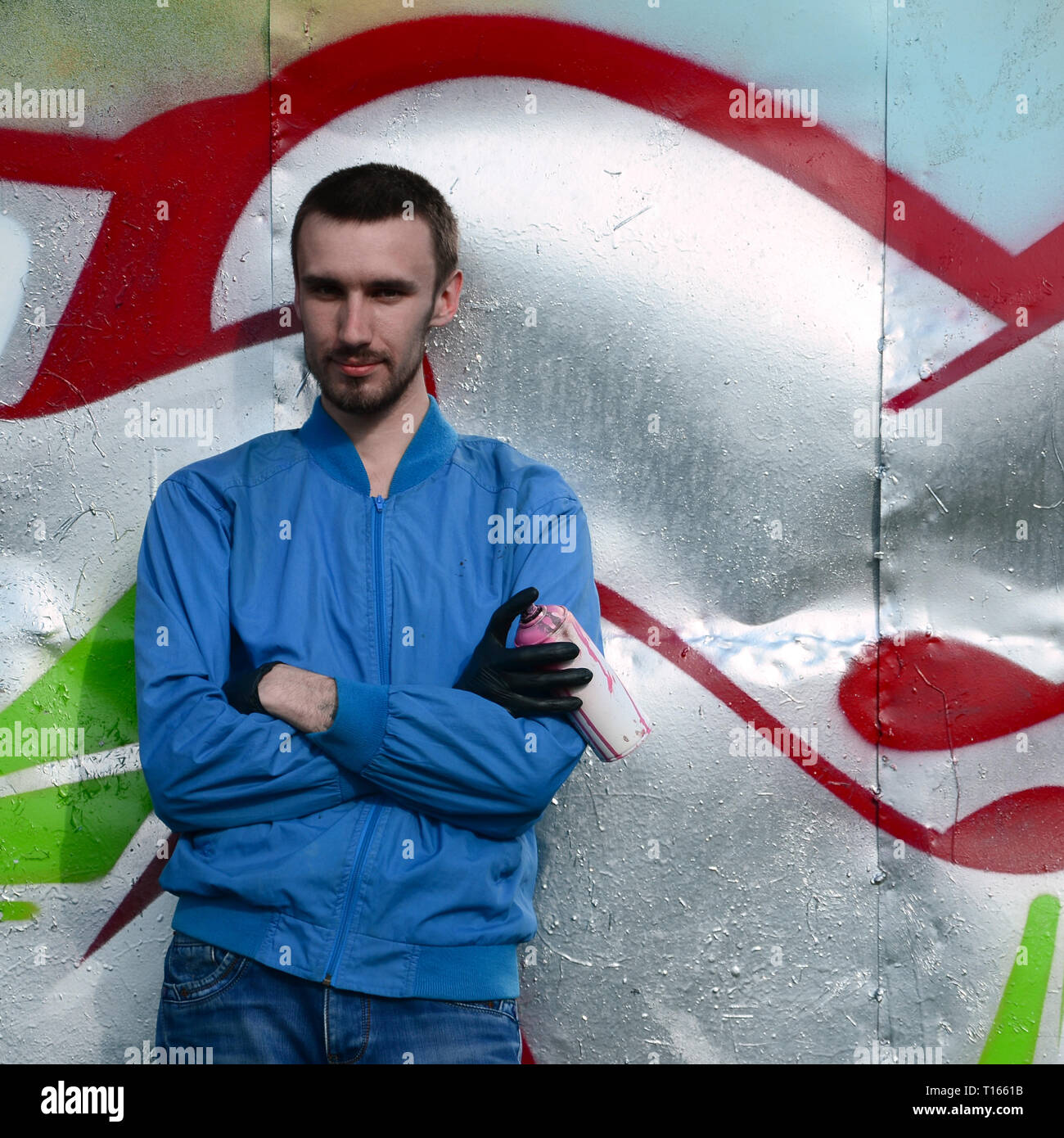 The graffiti artist with spray can poses against the background of a ...