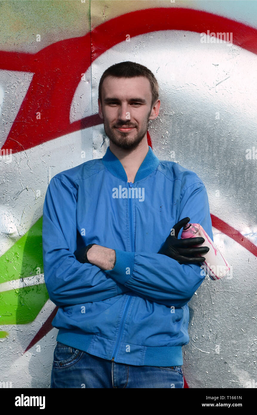 The graffiti artist with spray can poses against the background of a ...