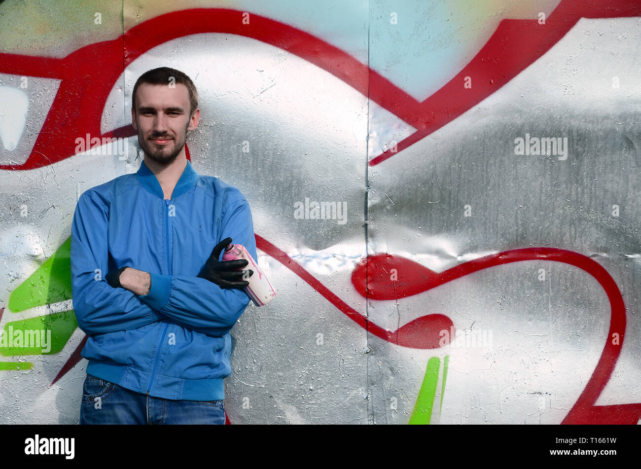 The graffiti artist with spray can poses against the background of a ...