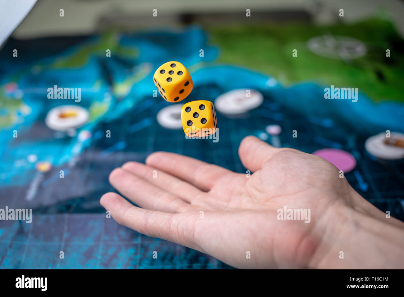 The hand throws two yellow dice on the playing field. Luck and excitement. The concept of Board games. Gaming moments in dynamics Stock Photo