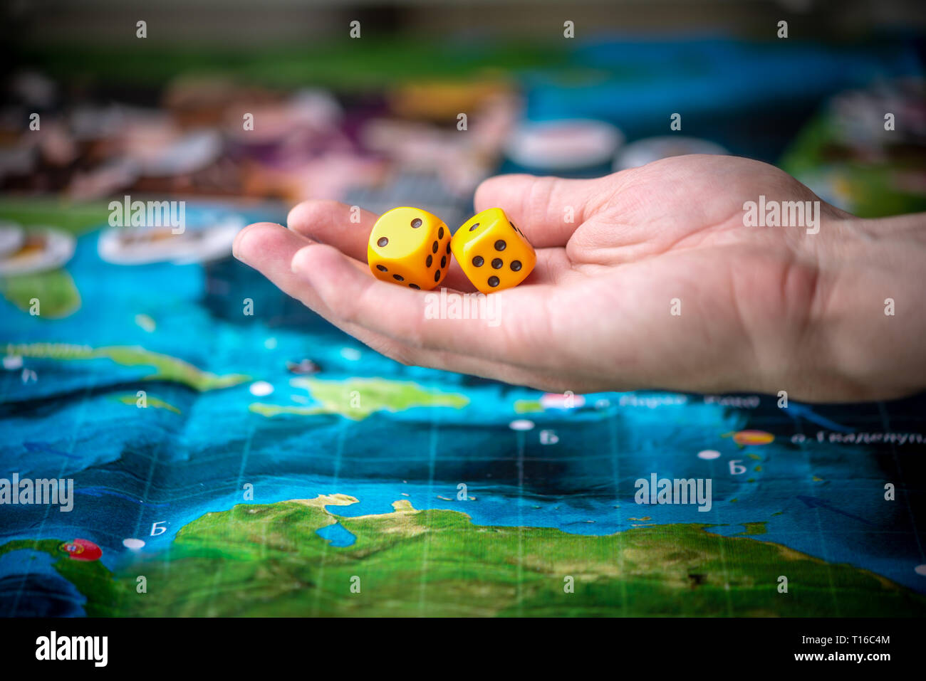 Hand throws two yellow dice on the playing field. Gaming moments in