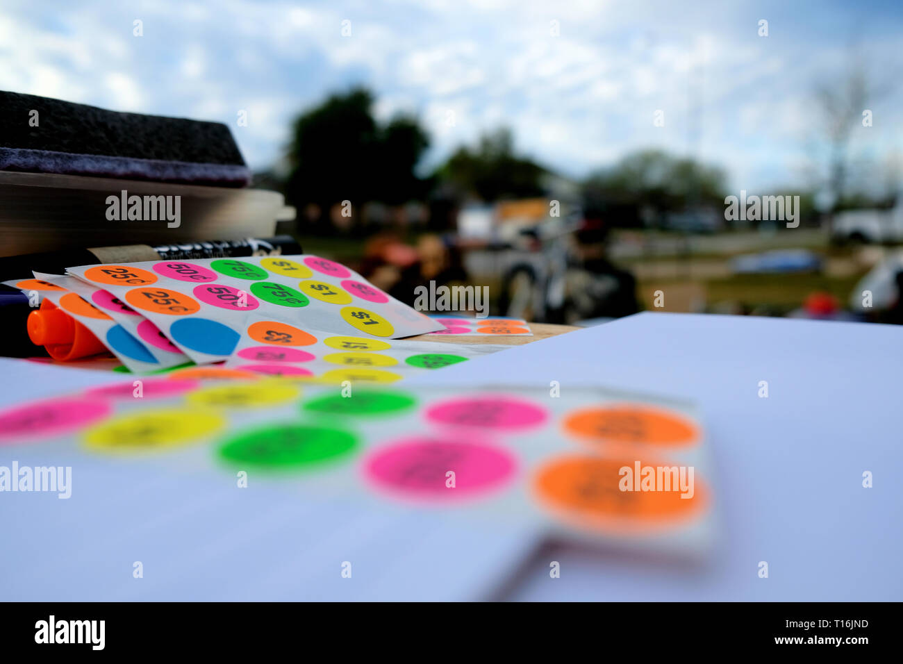 Colorful price tags with blurred garage sale in background; yard sale