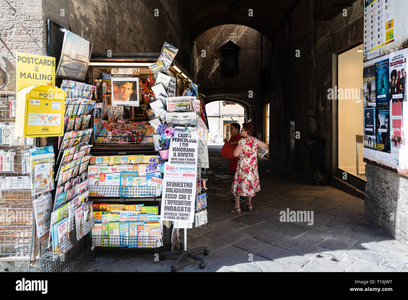 Siena, Italy - August 27, 2018: Historic medieval old town village in Tuscany with shopping souvenirs and map tour travel guide street vendor retail d Stock Photo