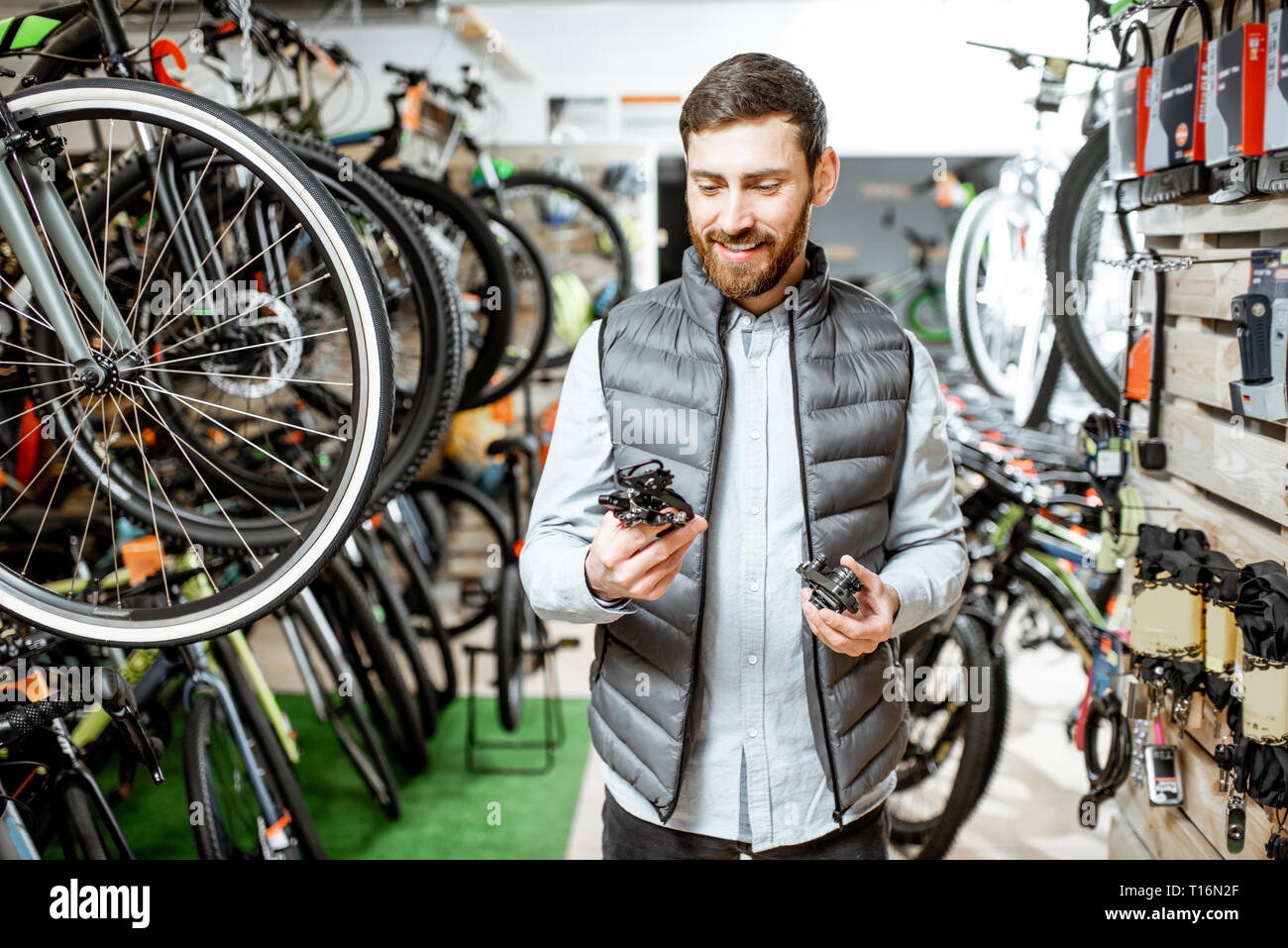 Man choosing bicycle parts standing in the store with lots of new bicycles  on the background Stock Photo - Alamy