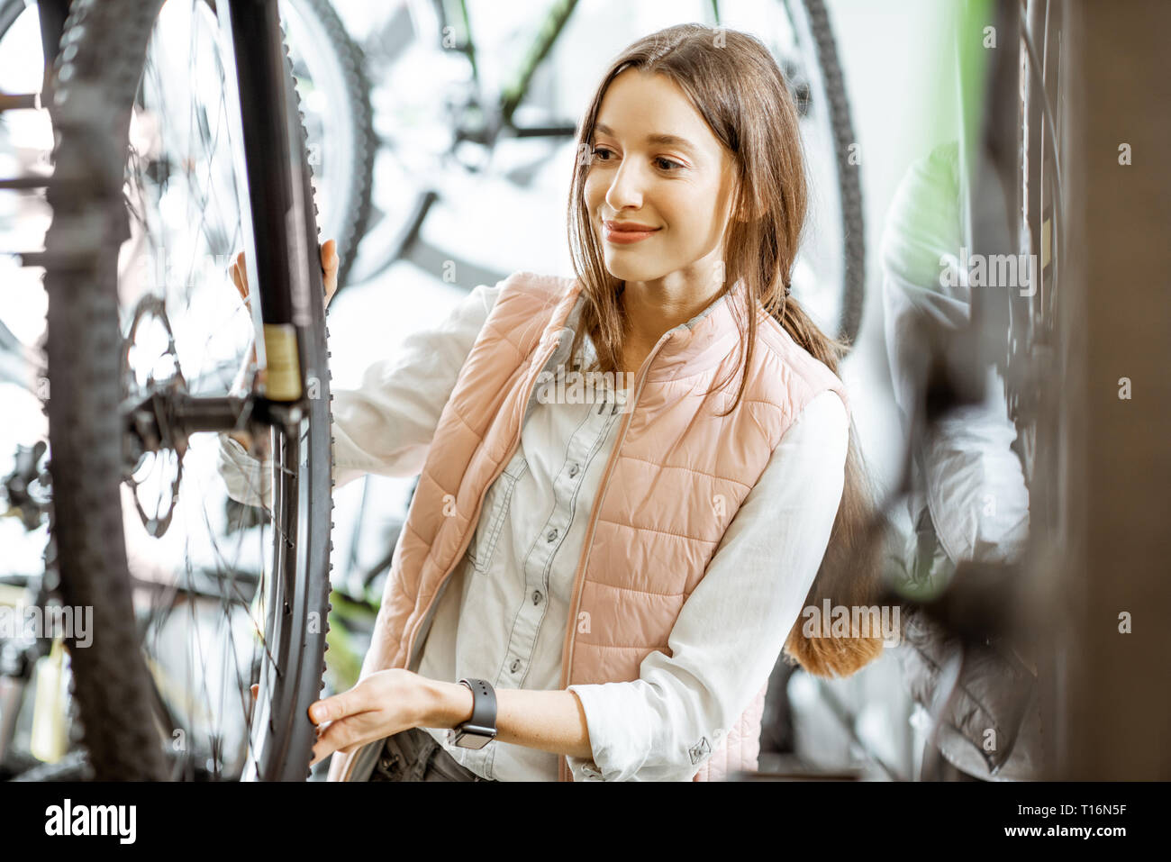 Young and beautiful woman choosing a new bicycle to buy at the bicycle store Stock Photo