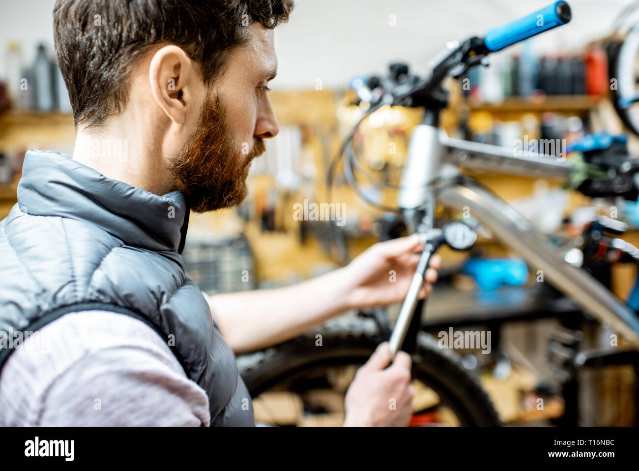 Repairman serving a bicycle, checking a air pressure in the pneumatic absorber of a fork in the workshop Stock Photo