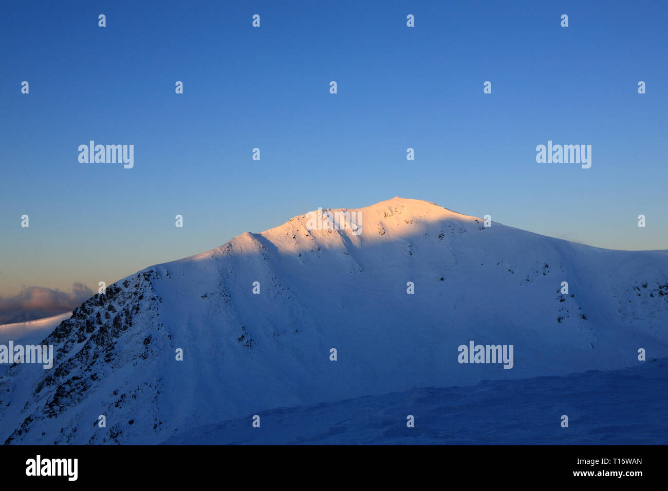 The first rays of the sun illuminate the top of the mountain ...