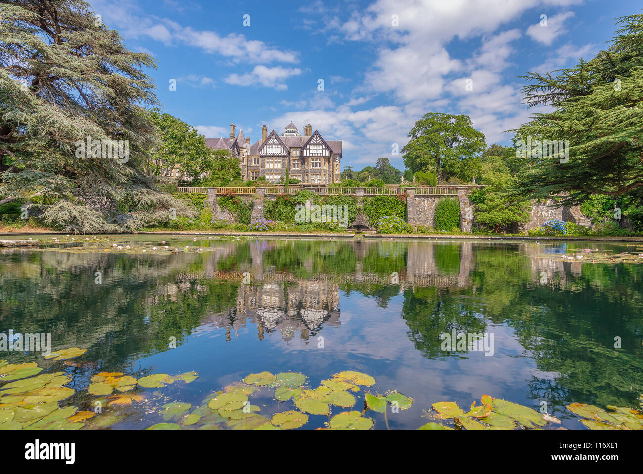 Bodnant Hall reflecting on a pond adorned with water lilies, Bodnant garden, Conwy, Wales, United Kingdom Stock Photo