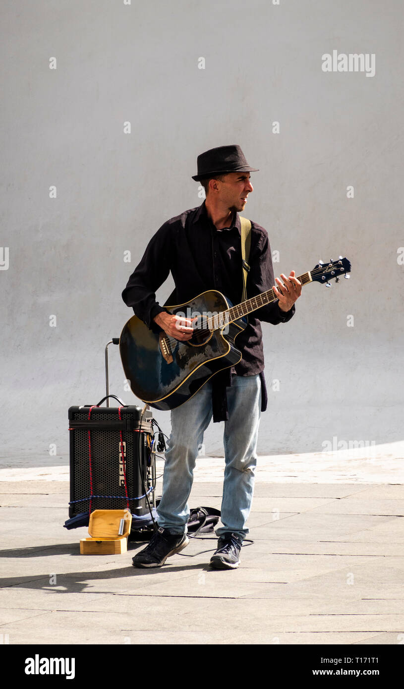 A busker playing the electric guitar on a street in Seville Stock Photo