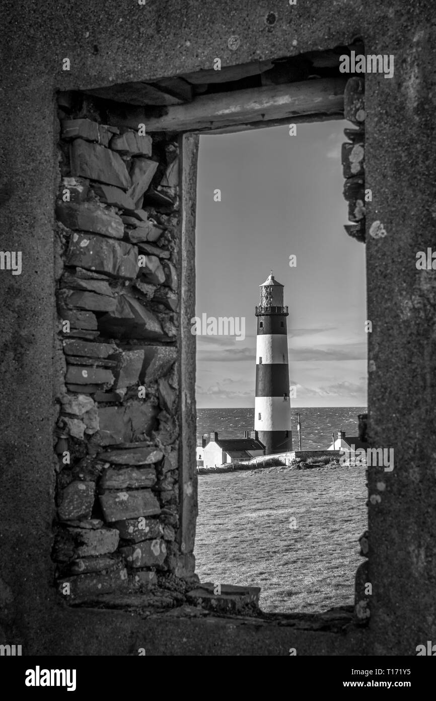 This is a picture of St John's Point Lighthouse  through a window of the ruins of an old coastguard station on the east coast of Northern Ireland on t Stock Photo