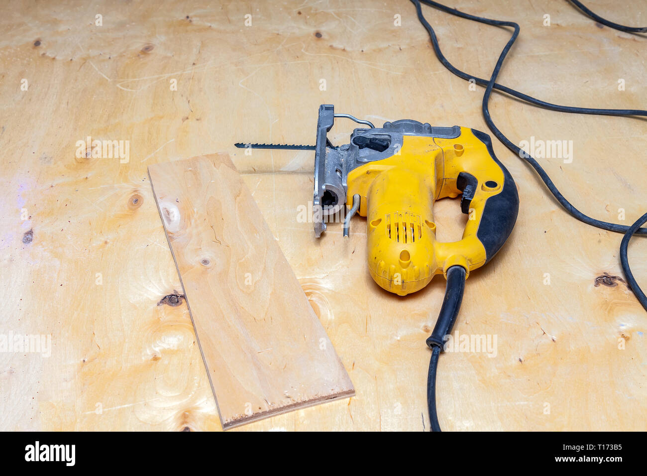 Flatlay of a yellow electric jigsaw ready for work use on the workbench