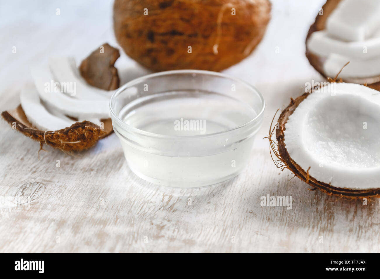 Whole coconut cut into chunks and chips and milk on a light white wooden background. Top view