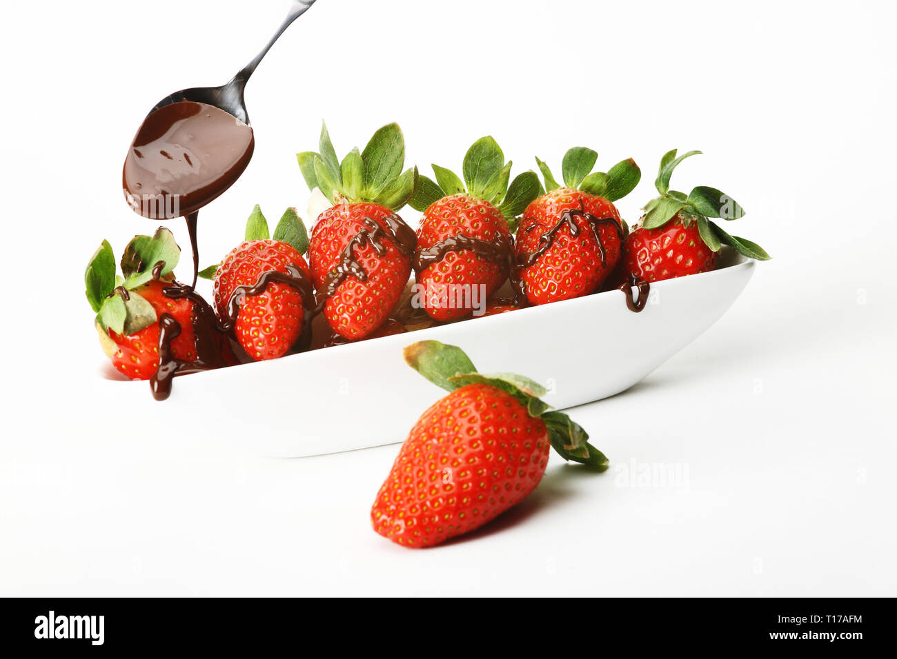 A bowl of strawberries covered with chocolate. Isolated against a white background. Stock Photo