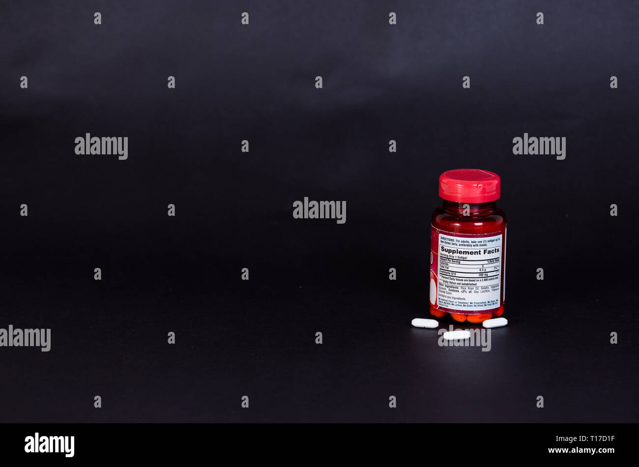 Drug bottle with capsules poured out with Black background Stock Photo