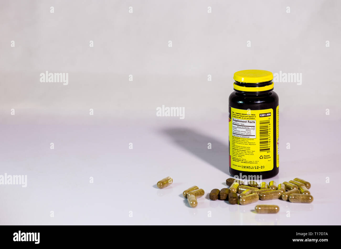Drug bottle with capsules poured out with white background Stock Photo