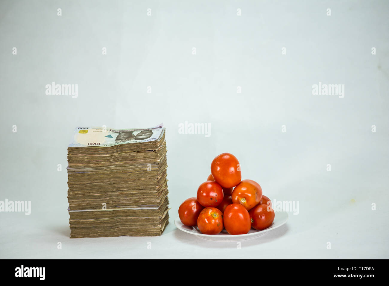 Stack of nigeria naira notes on white background wit tomatoes Stock Photo